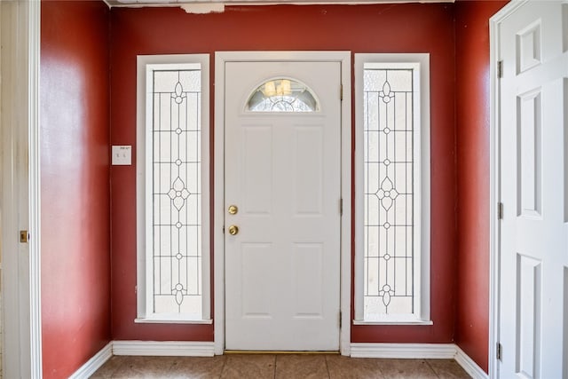 foyer entrance with light tile patterned floors and baseboards