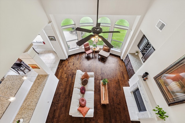 living room featuring ceiling fan, wood-type flooring, and a high ceiling