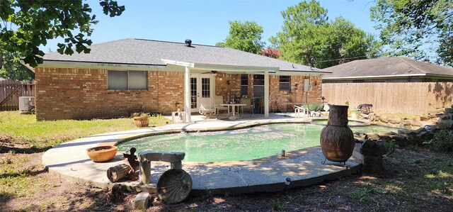 back of property with central air condition unit, a patio, and a fenced in pool