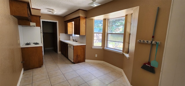 kitchen featuring white appliances, light countertops, a textured ceiling, a sink, and light tile patterned flooring