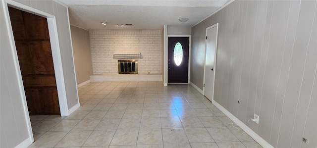 foyer entrance with light tile patterned floors, brick wall, a brick fireplace, and a textured ceiling