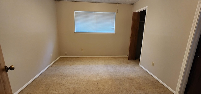 unfurnished bedroom featuring a closet, light carpet, and baseboards