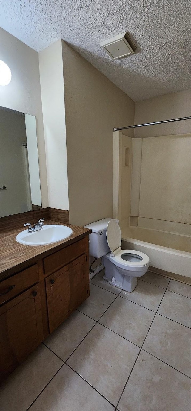 bathroom featuring a textured ceiling, tile patterned flooring, toilet, vanity, and shower / bathing tub combination