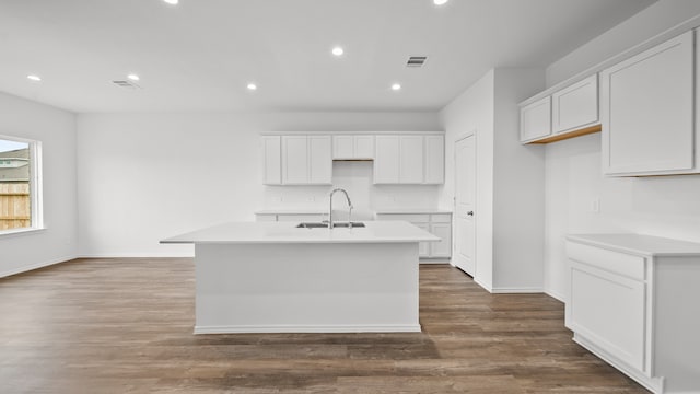 kitchen with white cabinetry, a kitchen island with sink, sink, and hardwood / wood-style flooring