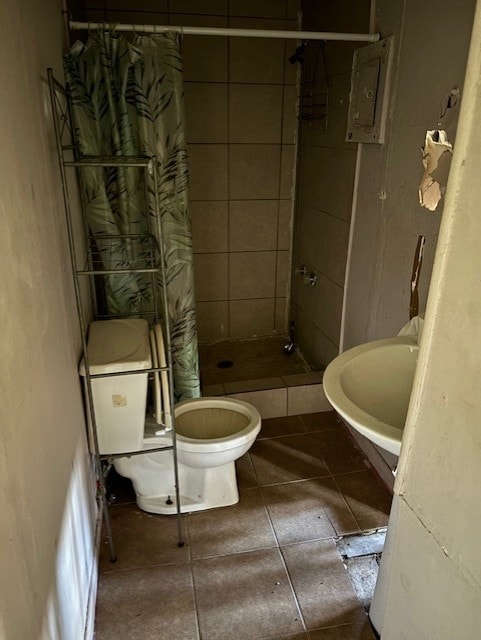 bathroom with a shower with curtain, electric panel, toilet, and tile patterned floors