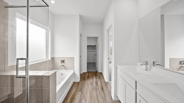 bathroom with wood-type flooring, vanity, and independent shower and bath