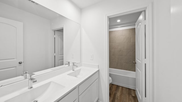 full bathroom with vanity, wood-type flooring, tiled shower / bath combo, and toilet