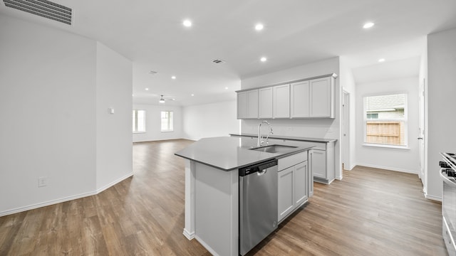 kitchen with dishwasher, a healthy amount of sunlight, sink, and an island with sink