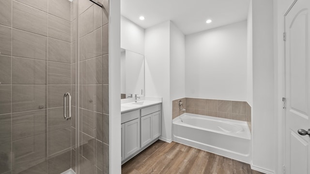 bathroom featuring wood-type flooring, vanity, and plus walk in shower