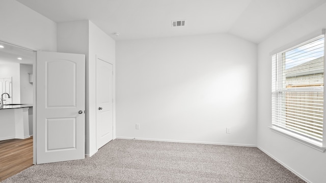 carpeted spare room with sink and lofted ceiling