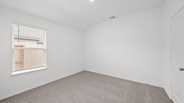 carpeted empty room featuring vaulted ceiling