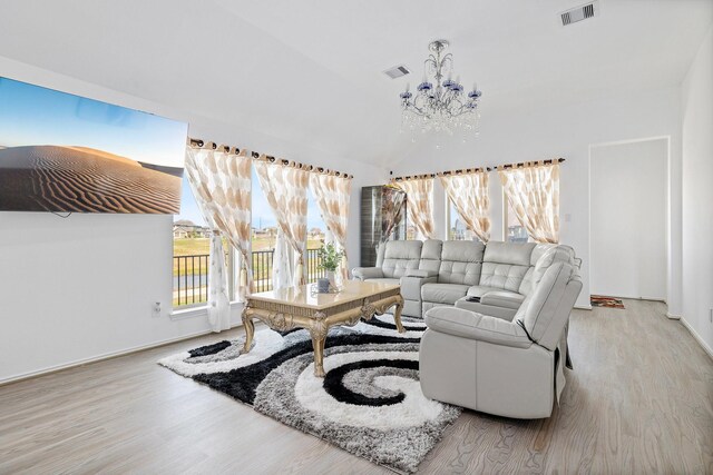 living room featuring lofted ceiling, light hardwood / wood-style flooring, and a chandelier