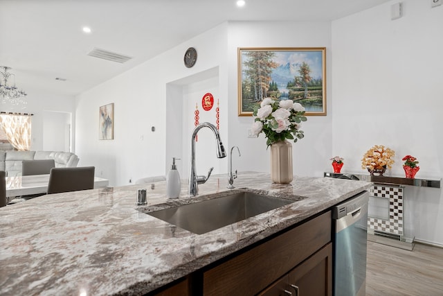 kitchen with dishwasher, sink, light stone countertops, dark brown cabinetry, and light hardwood / wood-style floors