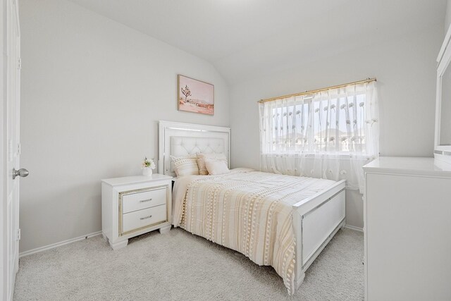 bedroom with lofted ceiling and light colored carpet