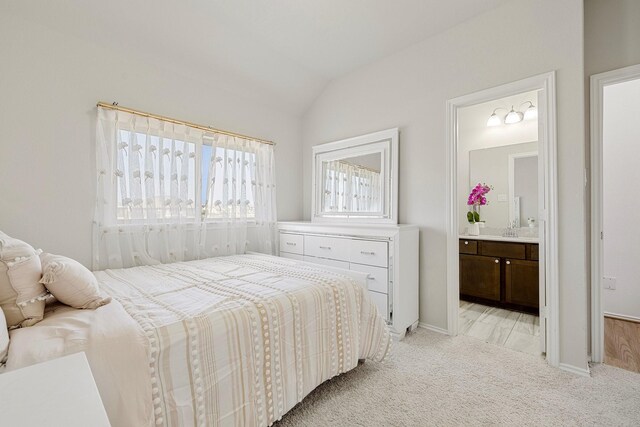 bedroom featuring connected bathroom, sink, vaulted ceiling, and light colored carpet