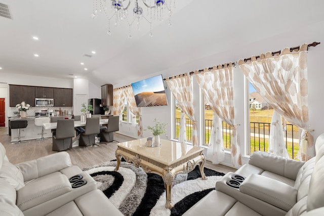 living room featuring lofted ceiling, a chandelier, and light wood-type flooring