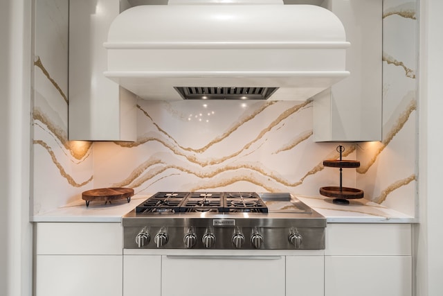 room details featuring white cabinets, premium range hood, and stainless steel gas cooktop