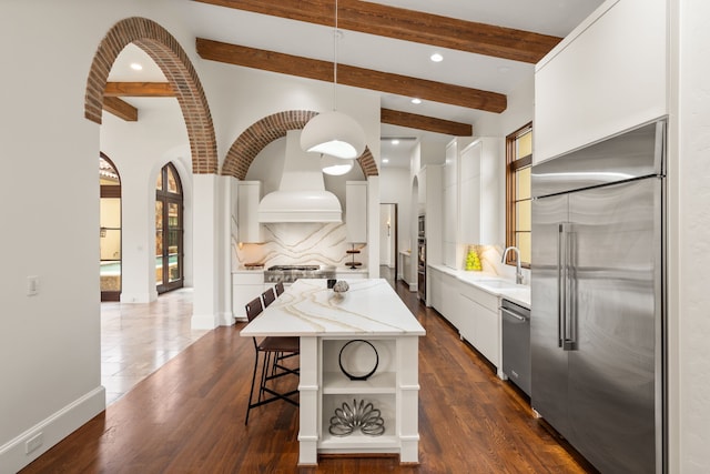 kitchen with white cabinets, hanging light fixtures, stainless steel appliances, a kitchen island, and tasteful backsplash