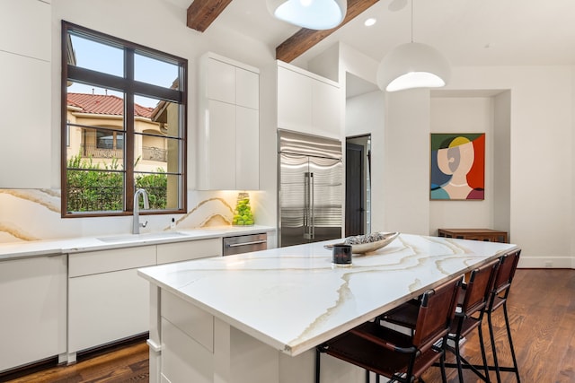 kitchen featuring decorative light fixtures, appliances with stainless steel finishes, white cabinetry, and sink