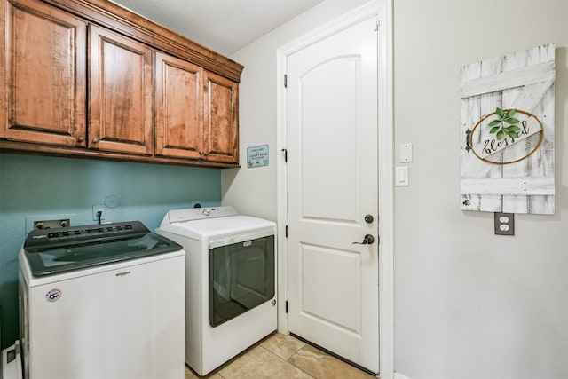 washroom featuring light tile patterned floors, cabinets, and washer and dryer