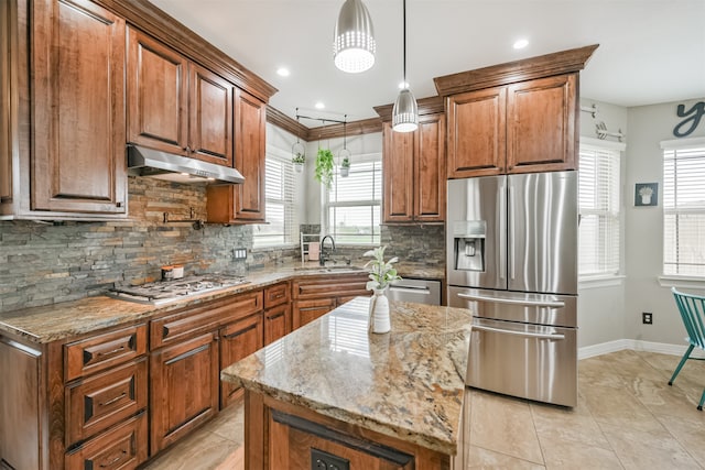 kitchen with appliances with stainless steel finishes, a healthy amount of sunlight, a center island, and pendant lighting