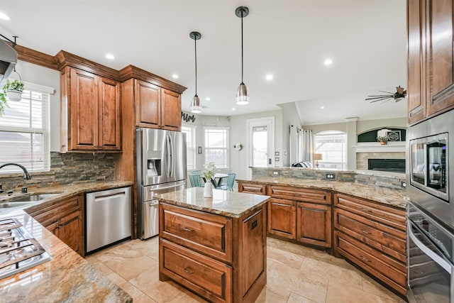 kitchen with a wealth of natural light, stainless steel appliances, sink, and hanging light fixtures