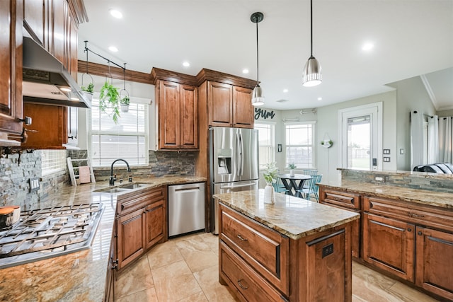 kitchen with stainless steel appliances, range hood, decorative light fixtures, light stone counters, and a kitchen island