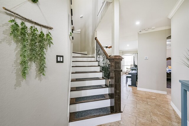 stairway with ornamental molding and tile patterned floors