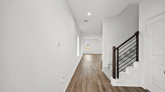 corridor featuring baseboards, visible vents, wood finished floors, stairs, and recessed lighting