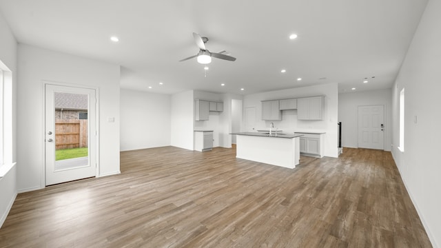 unfurnished living room with ceiling fan, light hardwood / wood-style floors, and sink