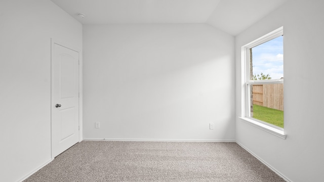 carpeted spare room with vaulted ceiling