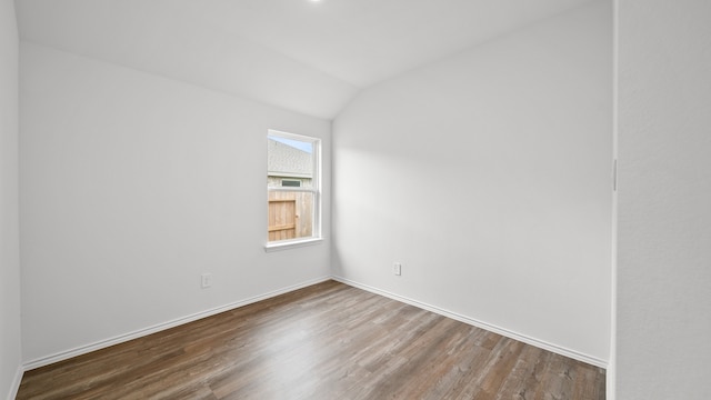 empty room with hardwood / wood-style floors and vaulted ceiling