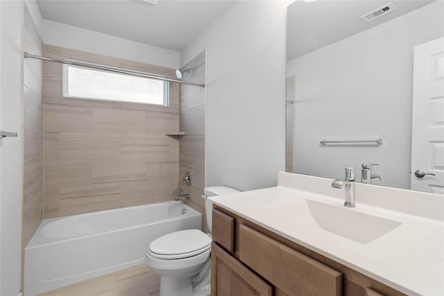 full bathroom featuring hardwood / wood-style floors, vanity, tiled shower / bath combo, and toilet