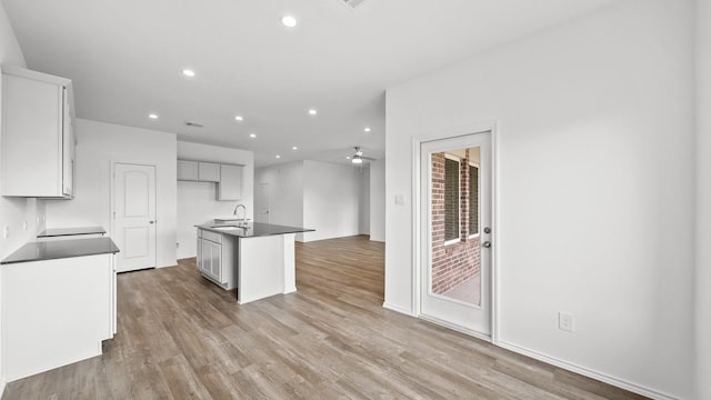 kitchen with ceiling fan, sink, an island with sink, and light wood-type flooring