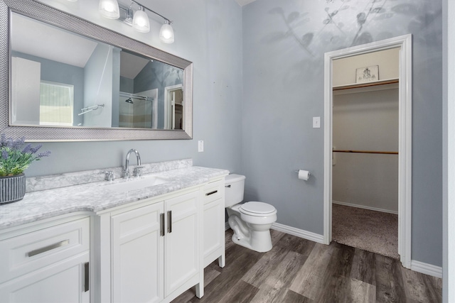 bathroom featuring hardwood / wood-style flooring, vanity, toilet, and a shower with shower door