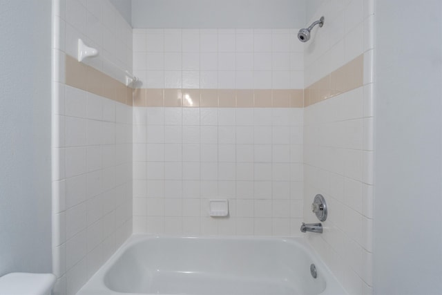 bathroom with toilet and tiled shower / bath