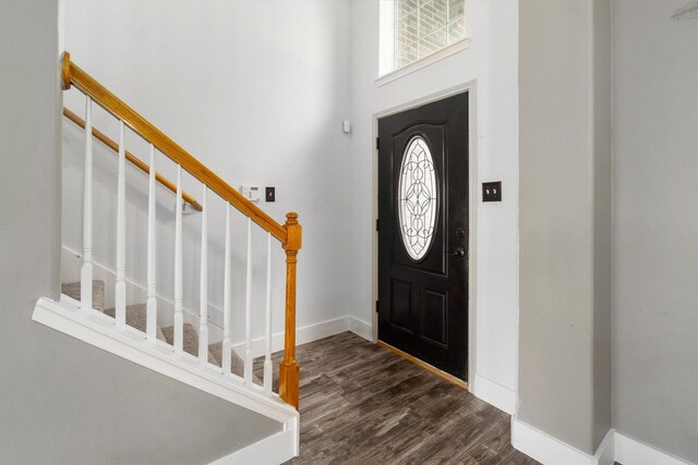 entryway with dark hardwood / wood-style floors and a towering ceiling