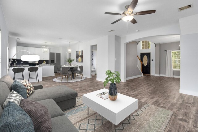 living room featuring wood-type flooring and ceiling fan with notable chandelier