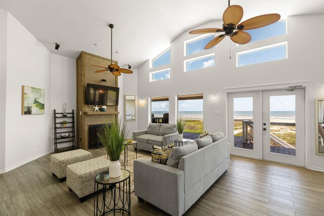 living room with french doors, hardwood / wood-style floors, a fireplace, high vaulted ceiling, and ceiling fan