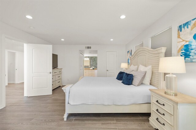 bedroom featuring ensuite bath and hardwood / wood-style flooring