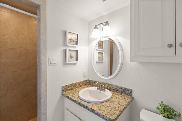 bathroom featuring vanity, toilet, and a tile shower