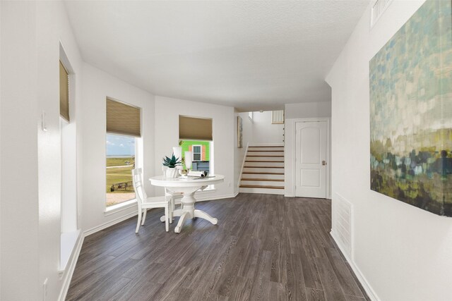 hallway with a textured ceiling and dark hardwood / wood-style flooring