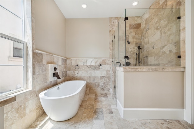 bathroom featuring shower with separate bathtub and tile walls