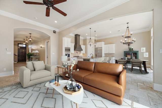 living room featuring ceiling fan with notable chandelier, ornamental molding, and sink