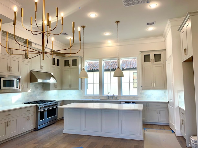 kitchen with stainless steel appliances, a kitchen island, hanging light fixtures, and decorative backsplash