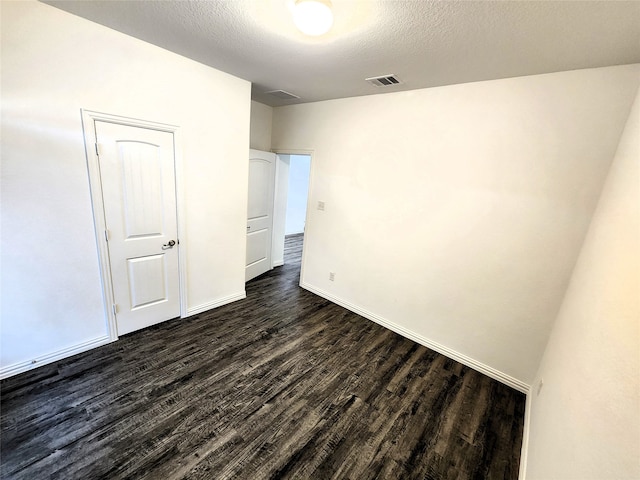 empty room with dark hardwood / wood-style flooring and a textured ceiling