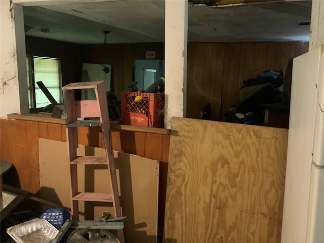 interior space featuring white refrigerator and wood walls