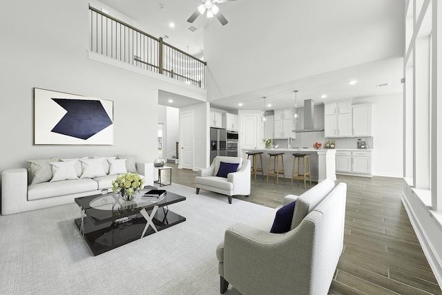 living room featuring hardwood / wood-style floors, ceiling fan, and a towering ceiling