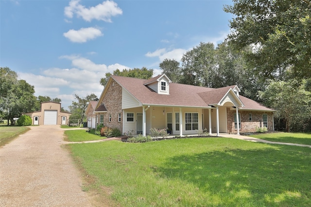 view of front of house featuring a garage, a porch, a front yard, and an outdoor structure