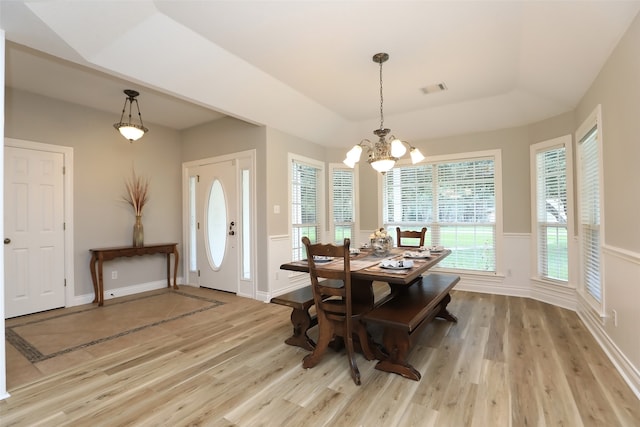 dining room with a notable chandelier, light hardwood / wood-style flooring, and a tray ceiling